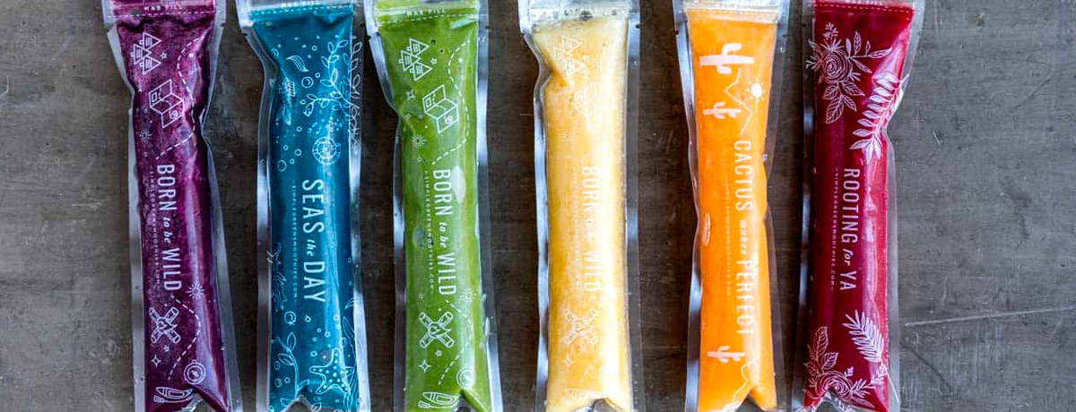 colorful homemade popsicles in plastic sleeves on a grey countertop