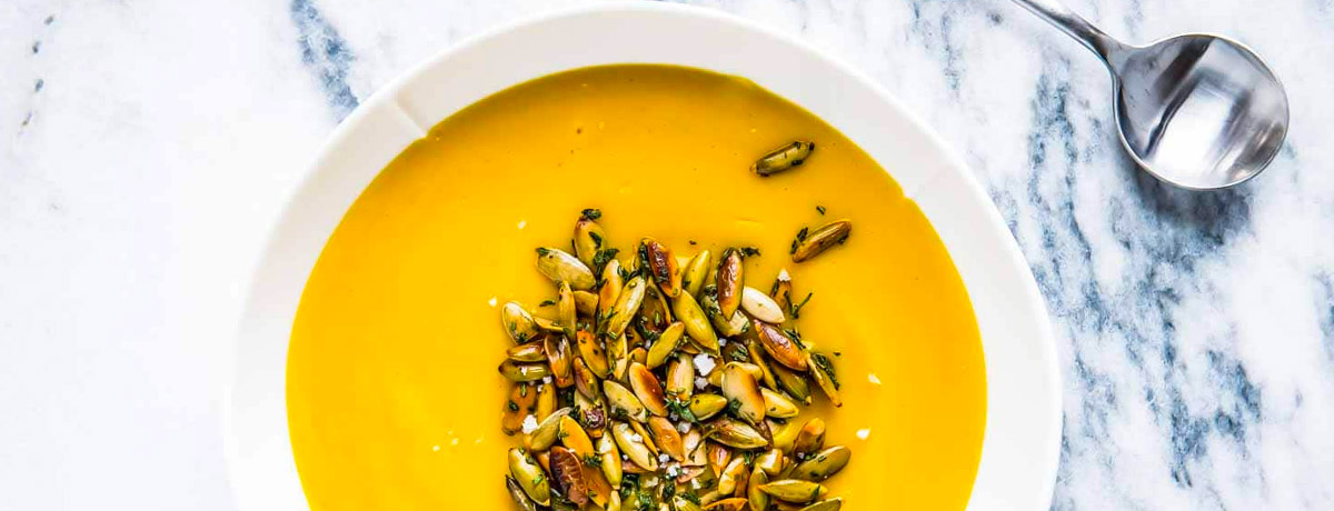 overhead shot of pumpkin soup with pumpkin seeds sprinkled in the middle