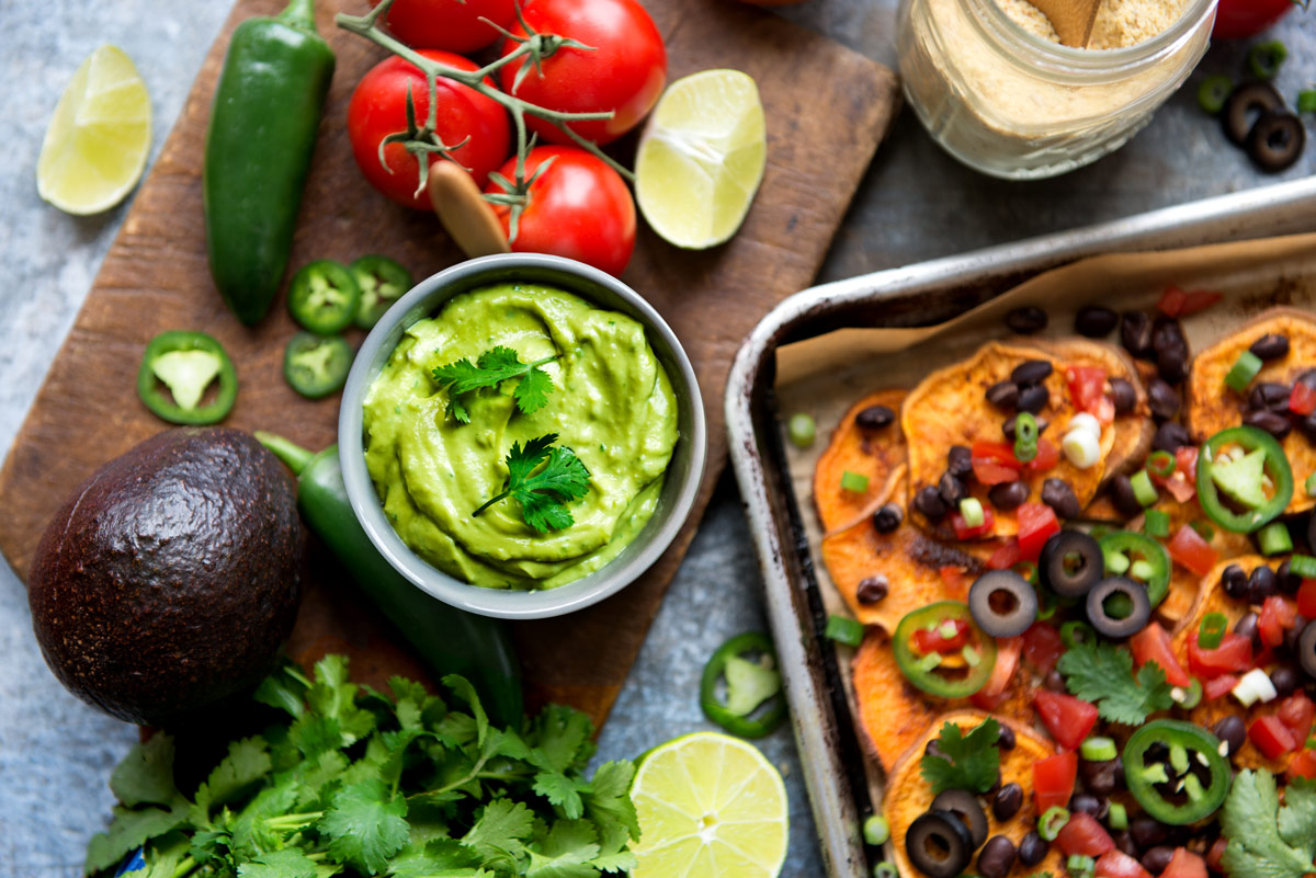 Nachos with bowl of avocado crema on table