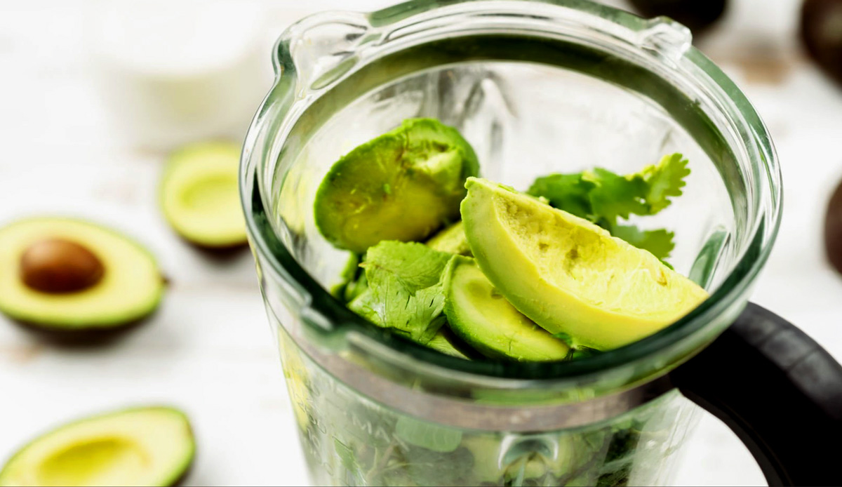 Blender with avocado and cilantro to make avocado crema.