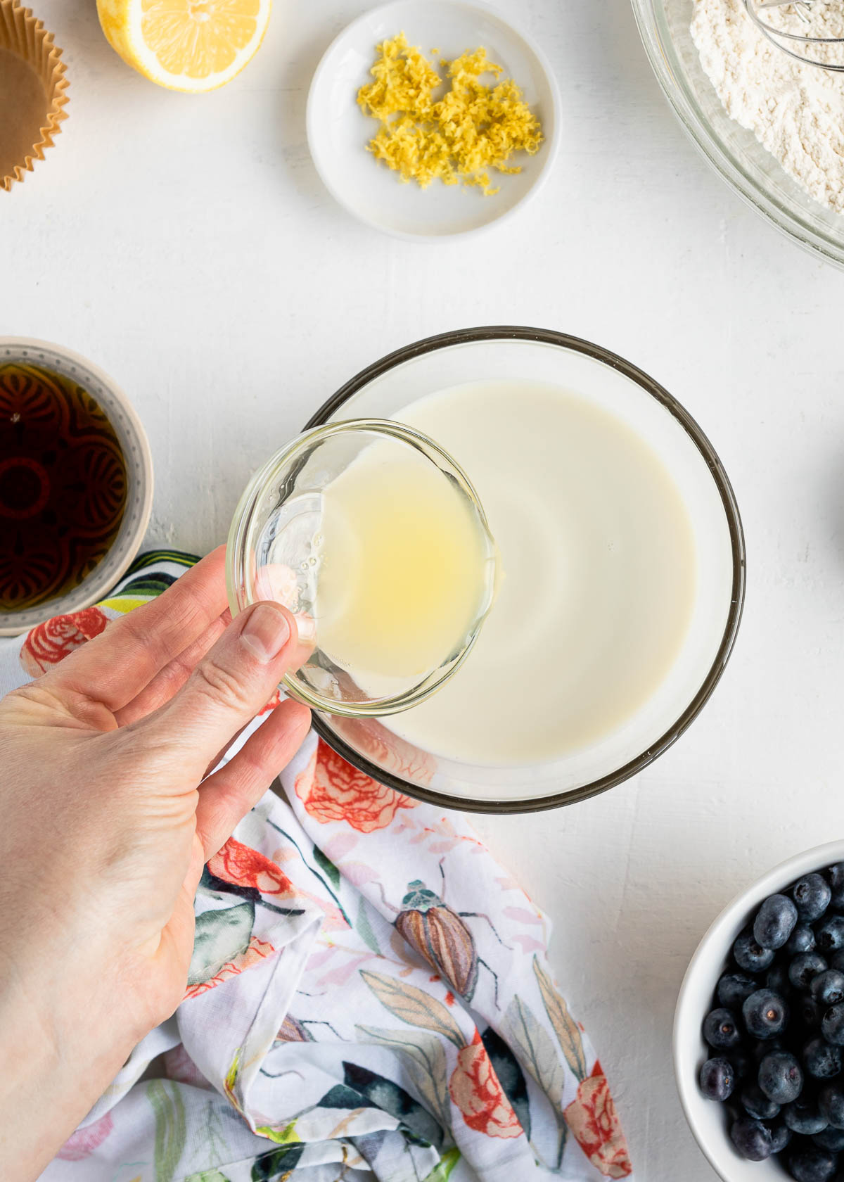 pouring lemon juice into oat milk to create vegan buttermilk.