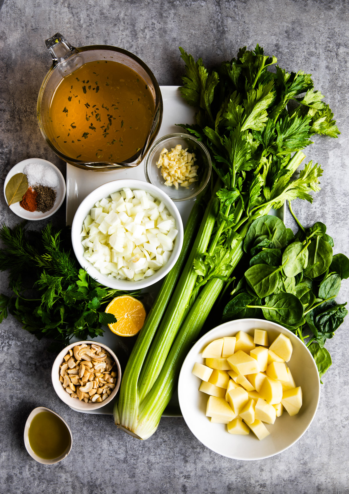 Ingredients to make a celery soup recipe on a gray table.