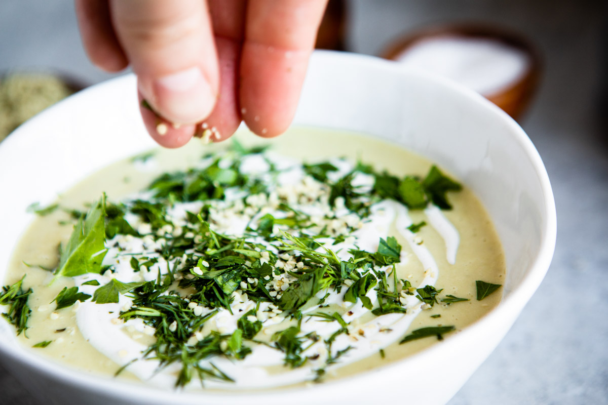 Sprinkling parsley into a bowl of celery soup.