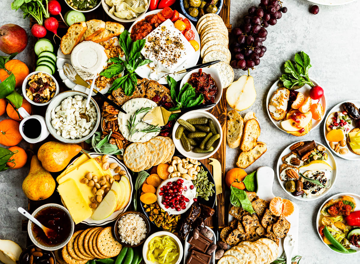 large board of vegan charcuterie with a variety of unique dips, plant-based cheeses and fresh fruits.