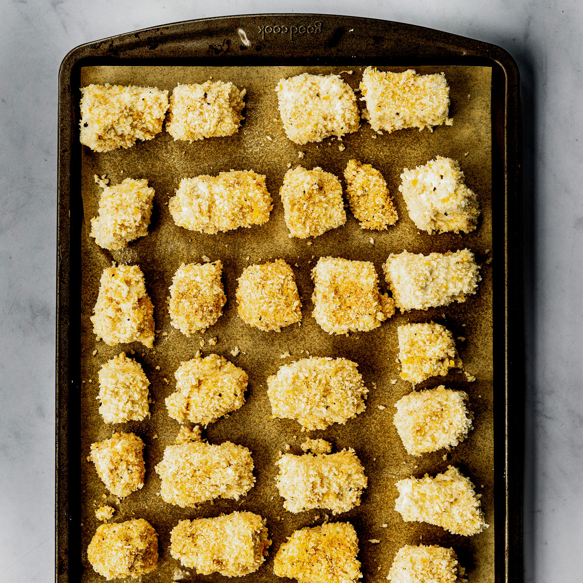 Baking sheet with breaded vegan chicken nuggets ready to go in the oven.