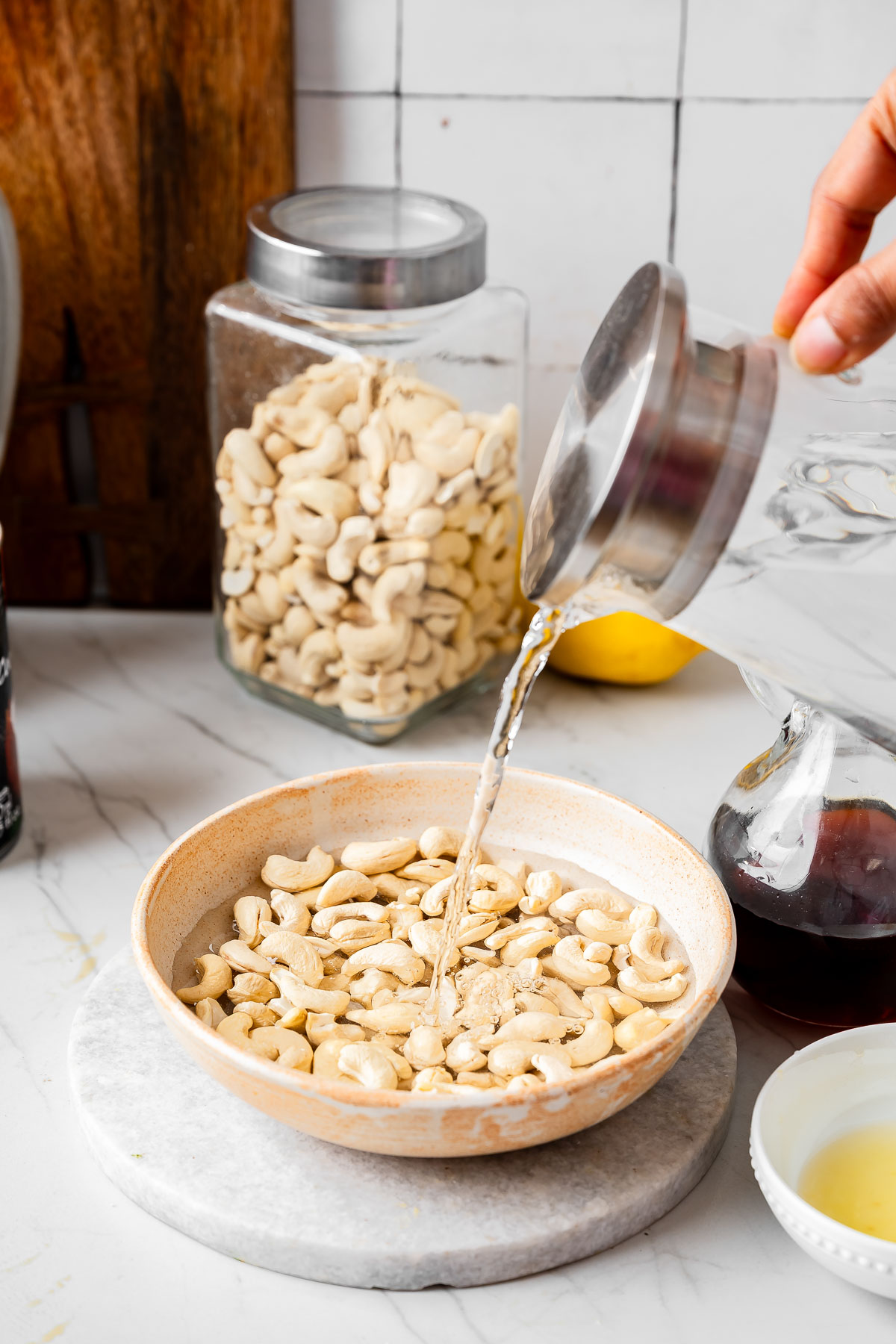 A person adding water into a bowl of cashews