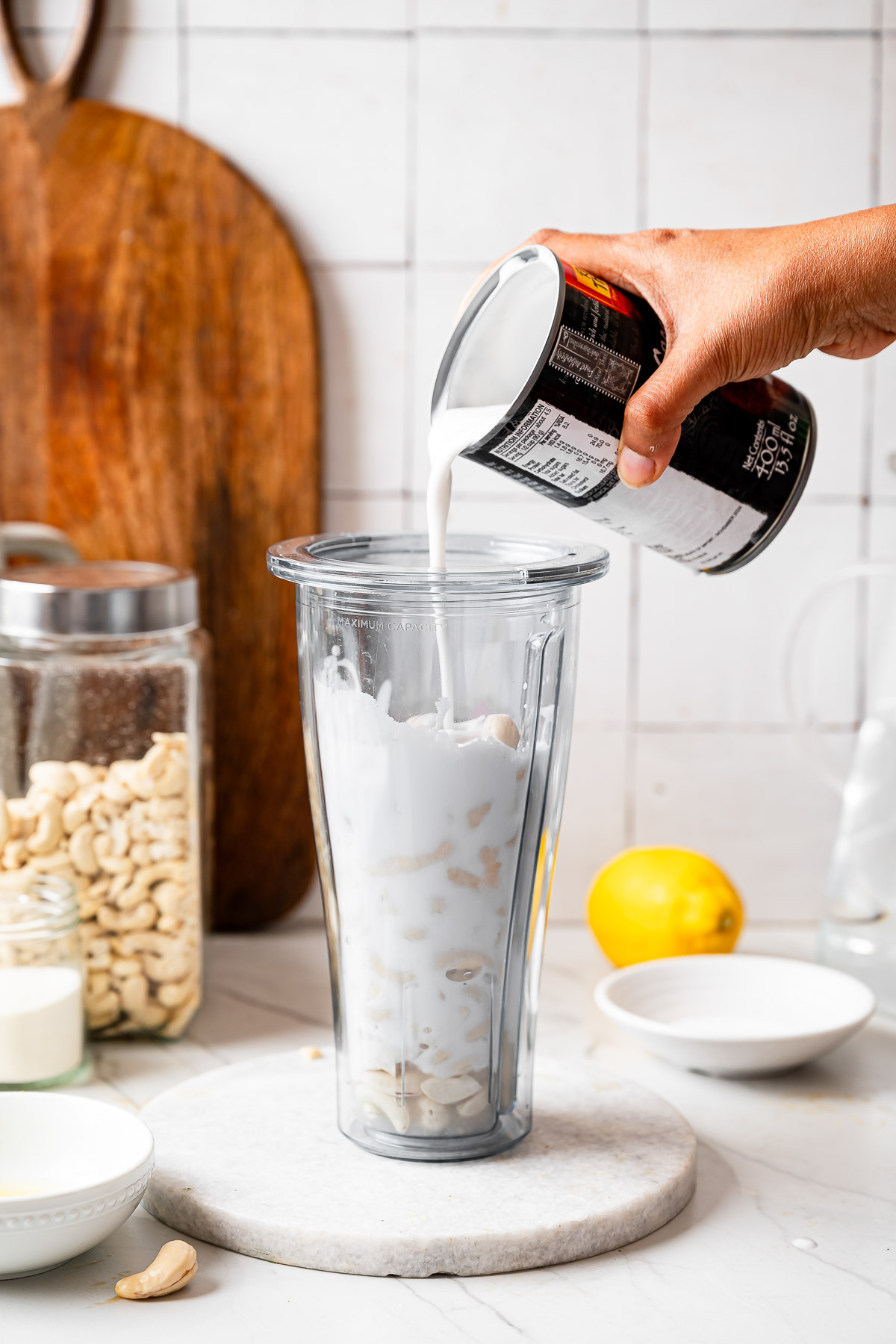 A person pouring coconut cream into a blender