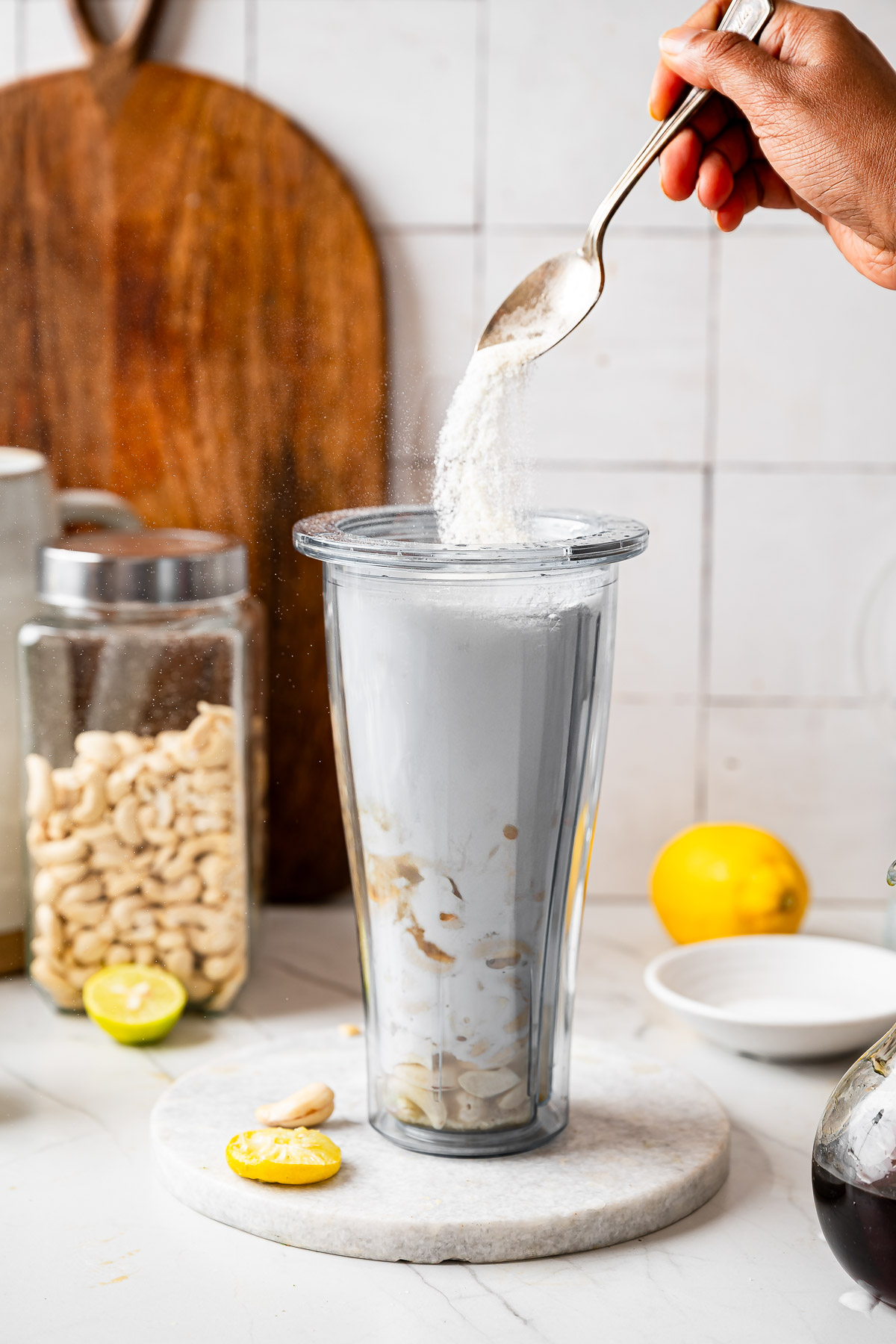 A person adding sea salt into a blender mixture