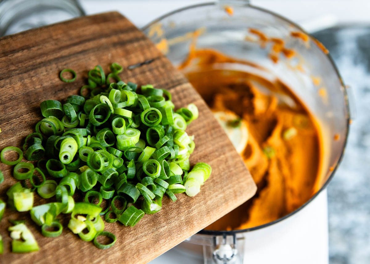 mixing green onions into vegan cashew cream mixture.