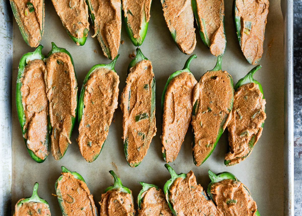 spreading vegan cashew cream onto jalapenos.