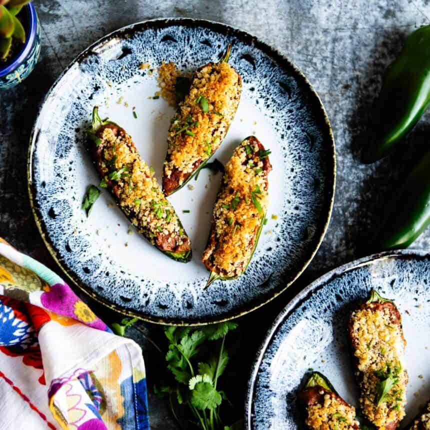 Blue pottery plates with vegan jalapeño peppers on them and floral napkins to the side.