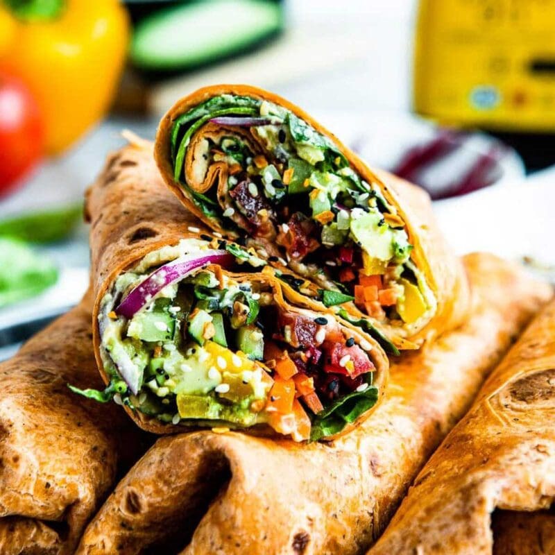 Halved vegetable wrap piled on other wraps.