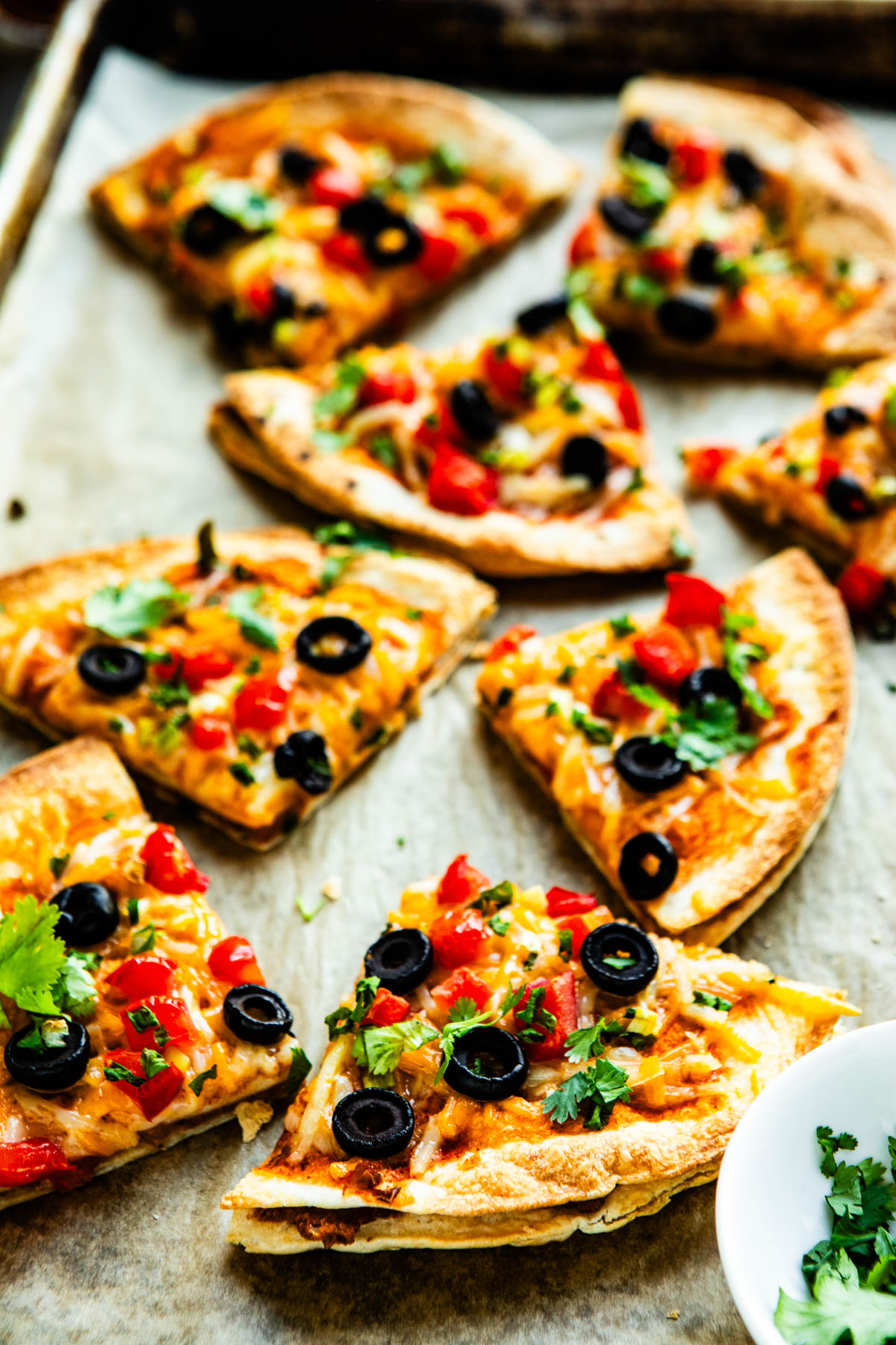 homemade Mexican pizza slices on a parchment lined baking sheet.