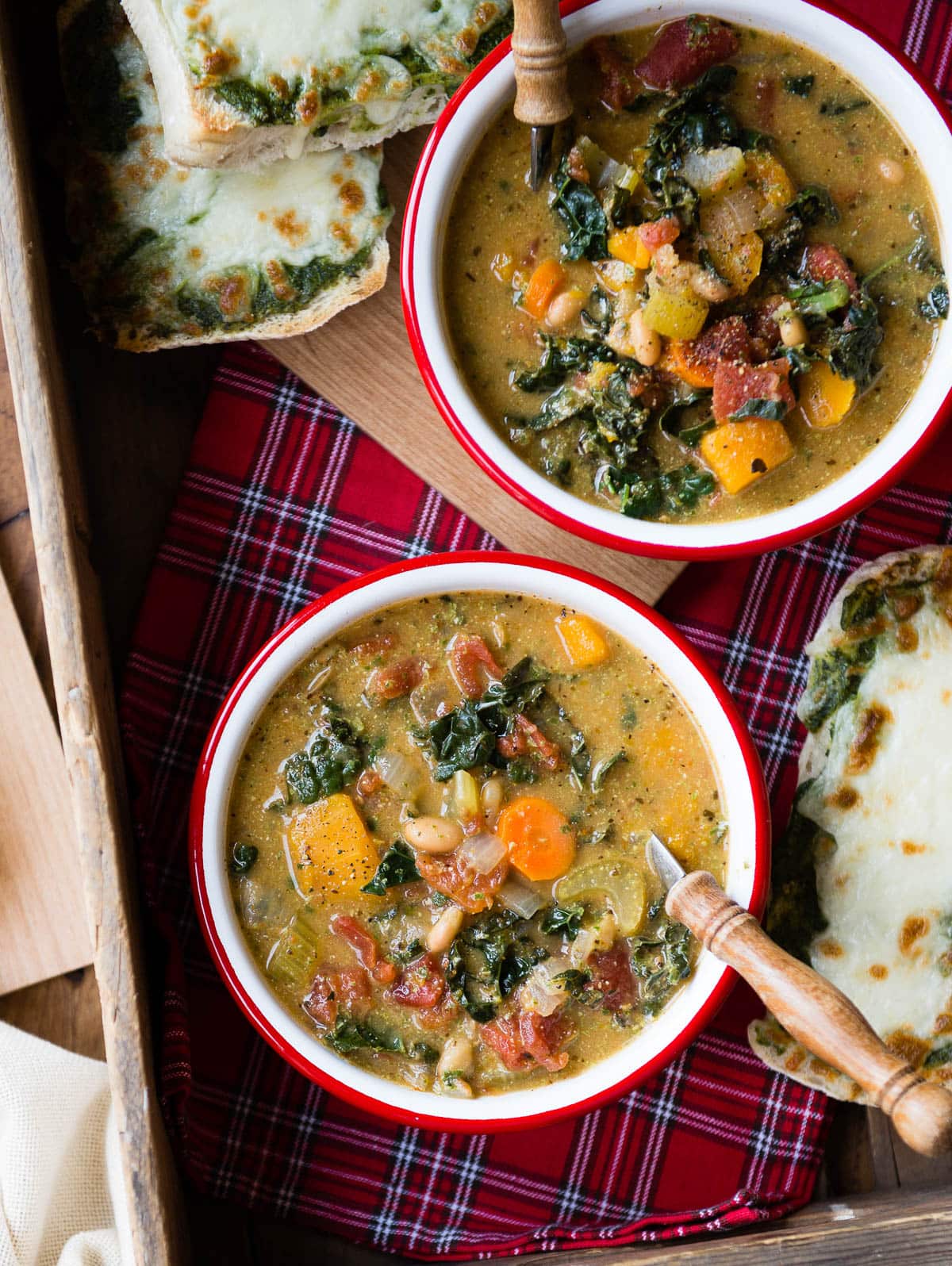 2 bowls of autumn vegetable soup  with wooden spoons.