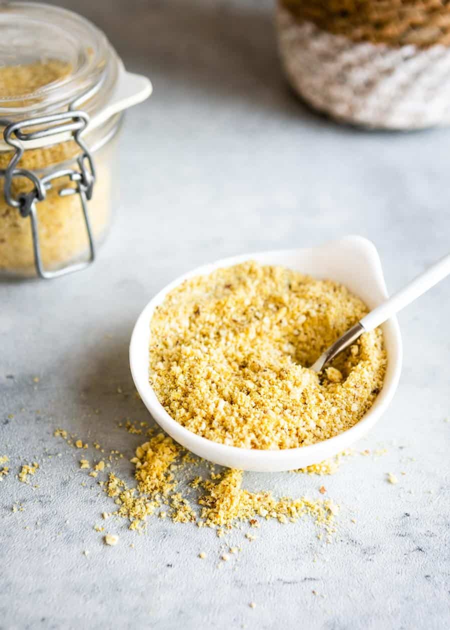 vegan parmesan cheese in a white bowl with a spoon.