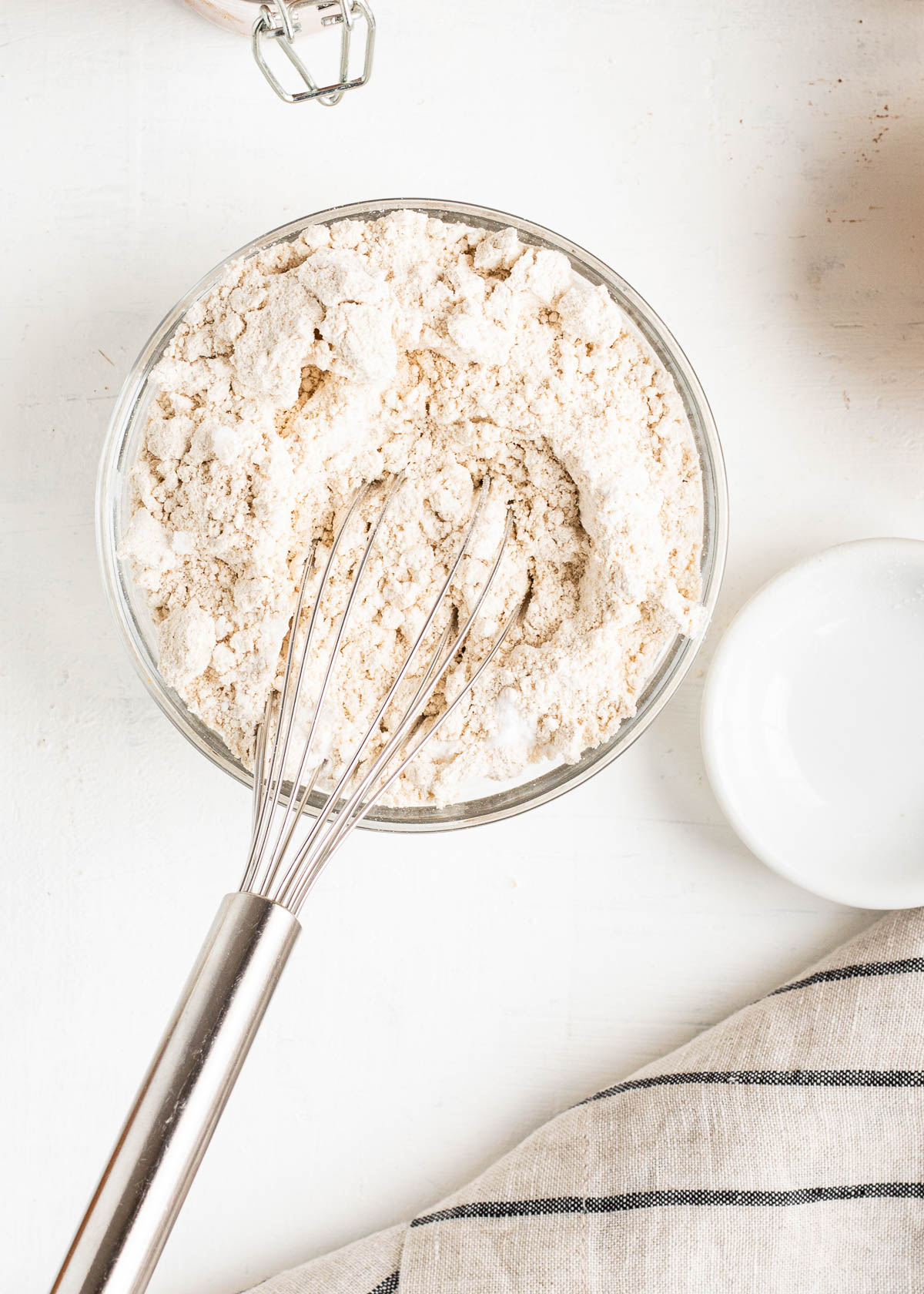 stainless steel whisk in a bowl of oat flour and other ingredients in gluten-free peanut butter cookies.