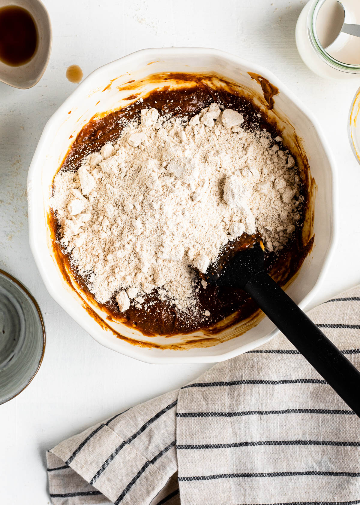 white mixing bowl of ingredients and a black spatula.