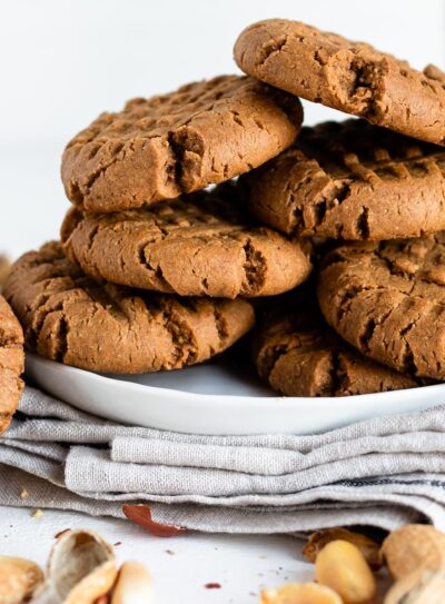 stack of vegan peanut butter cookies on a white plate on a white counter.