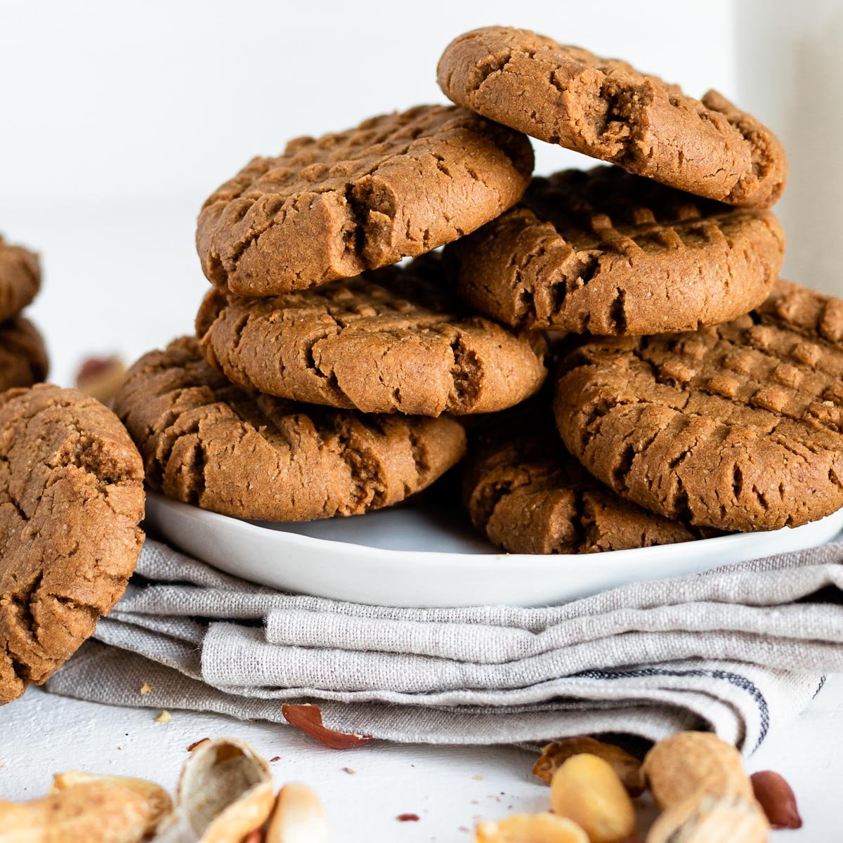 stack of vegan peanut butter cookies on a white plate on a white counter.