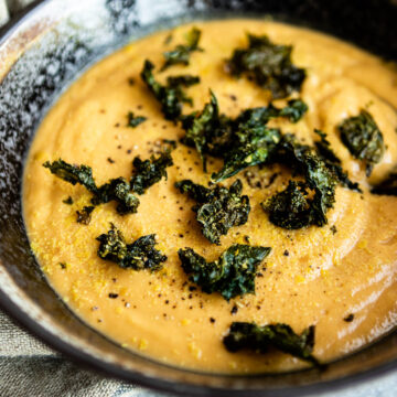 close up photo of a bowl of vegan potato soup topped with crunchy kale croutons