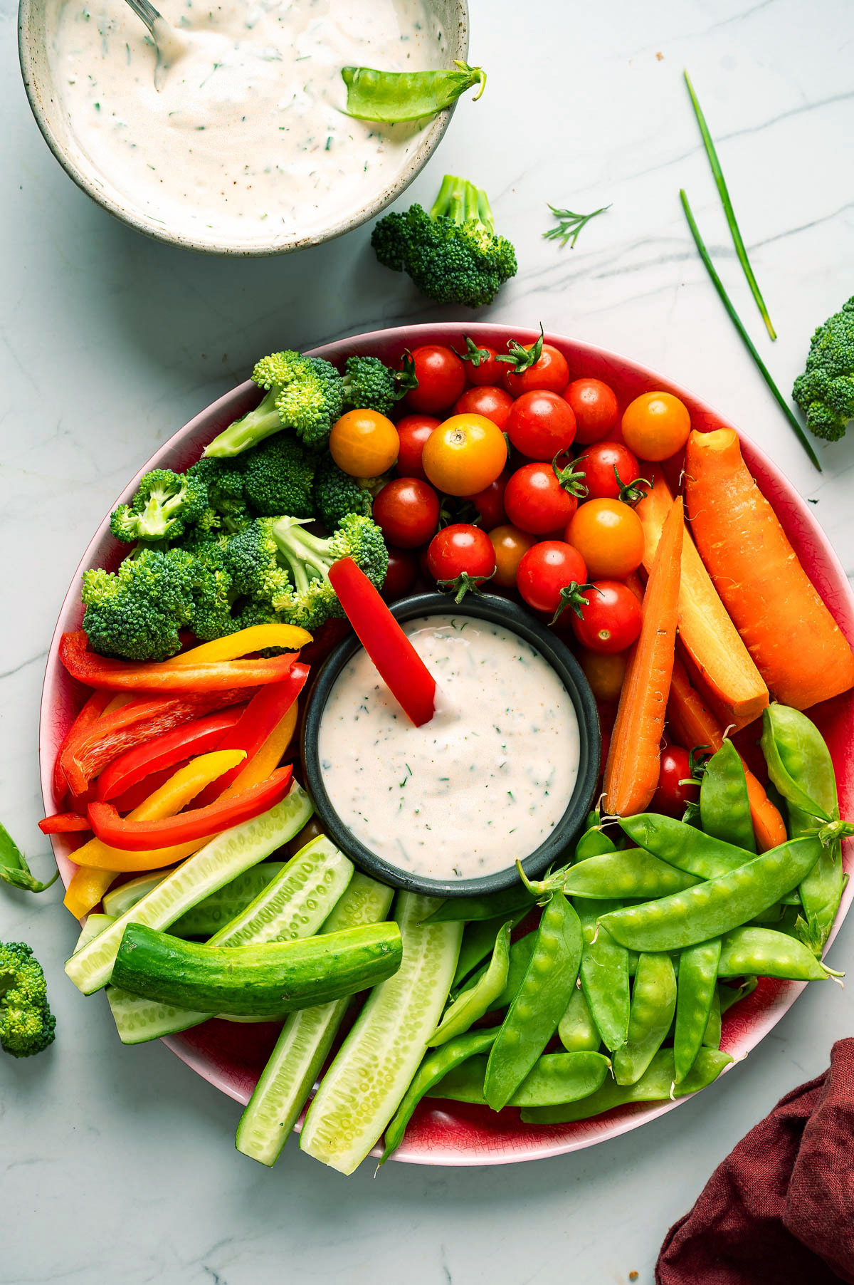 A bowl of vegan ranch dip surrounded by fresh veggies.