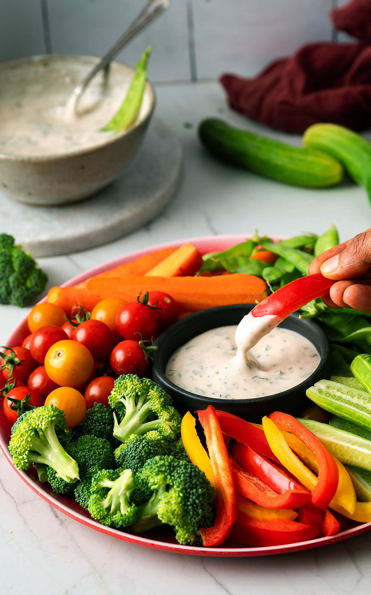 Dipping red bell pepper stick in vegan ranch dip.