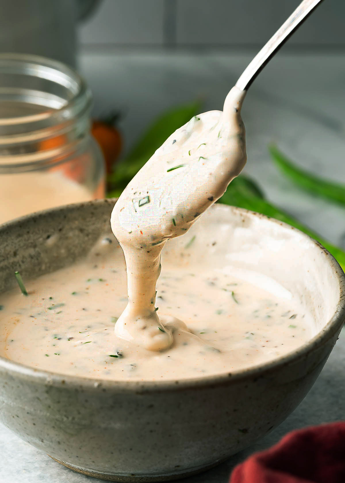 Creamy ranch dip dripping from a spoon back into the bowl. 