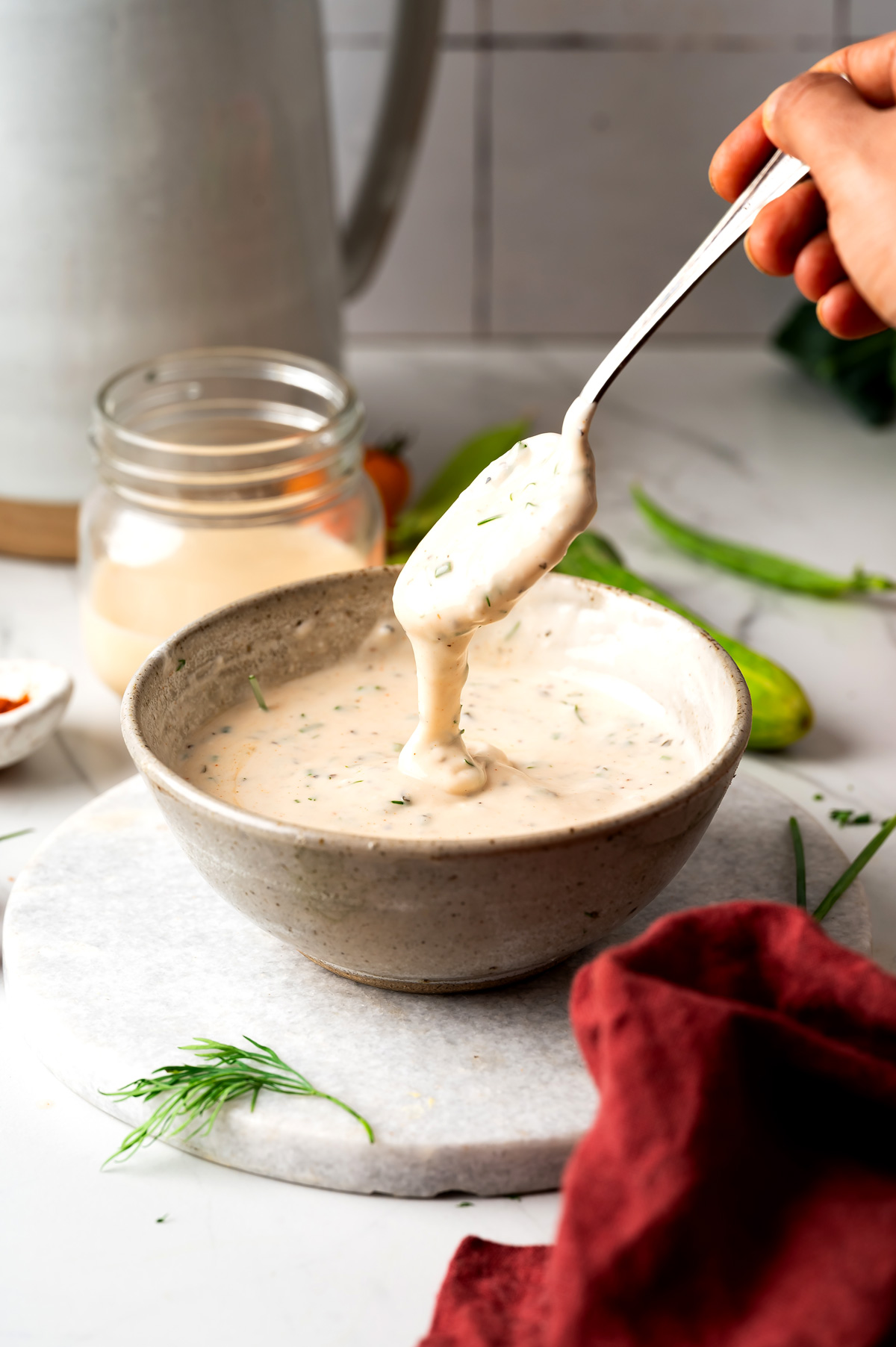 Creamy ranch dip dripping from a spoon back into the bowl