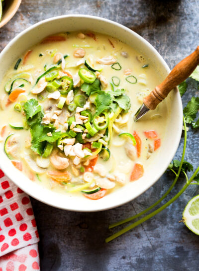 bowl of thai coconut soup on table with fresh-cut limes.
