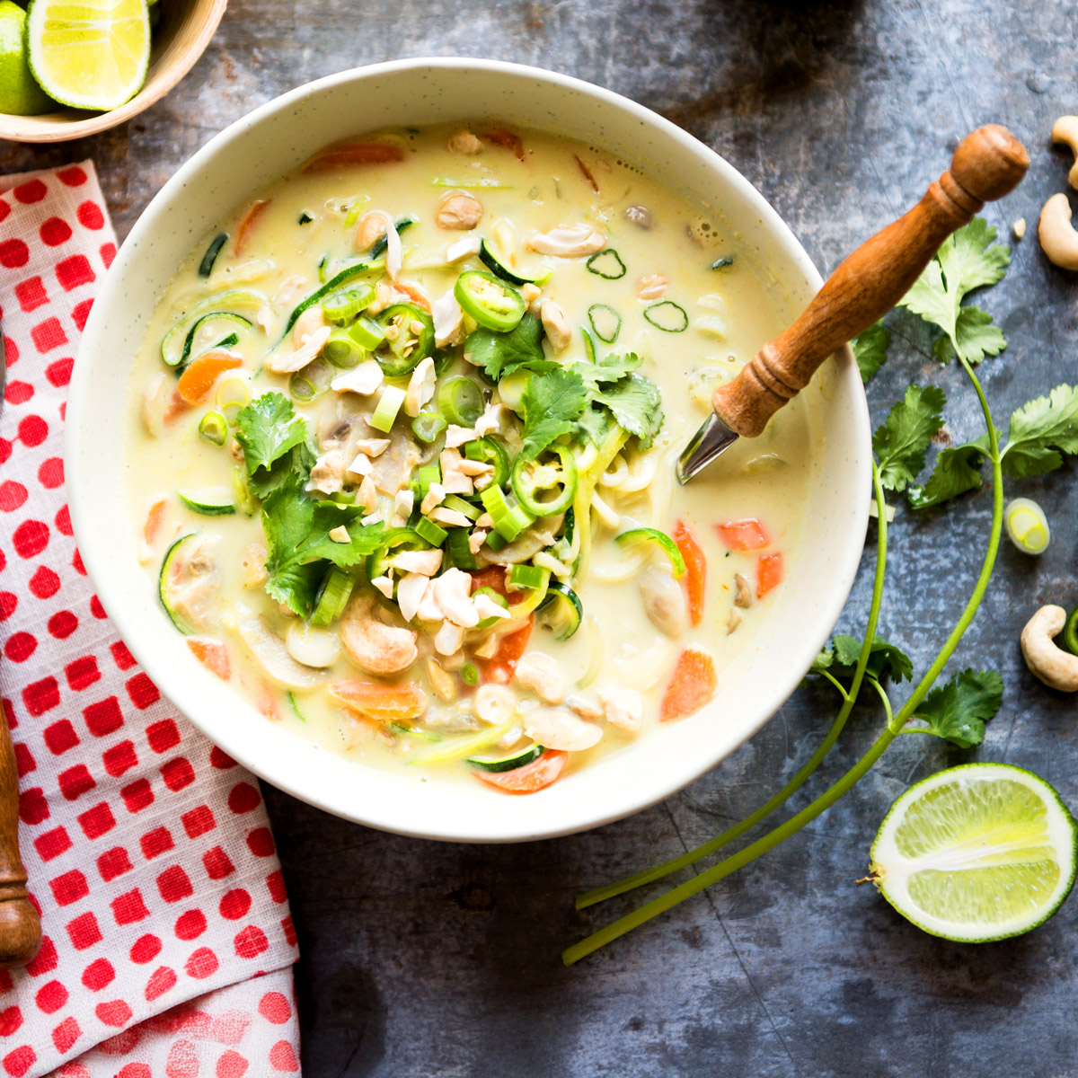 bowl of thai coconut soup on table with fresh-cut limes.