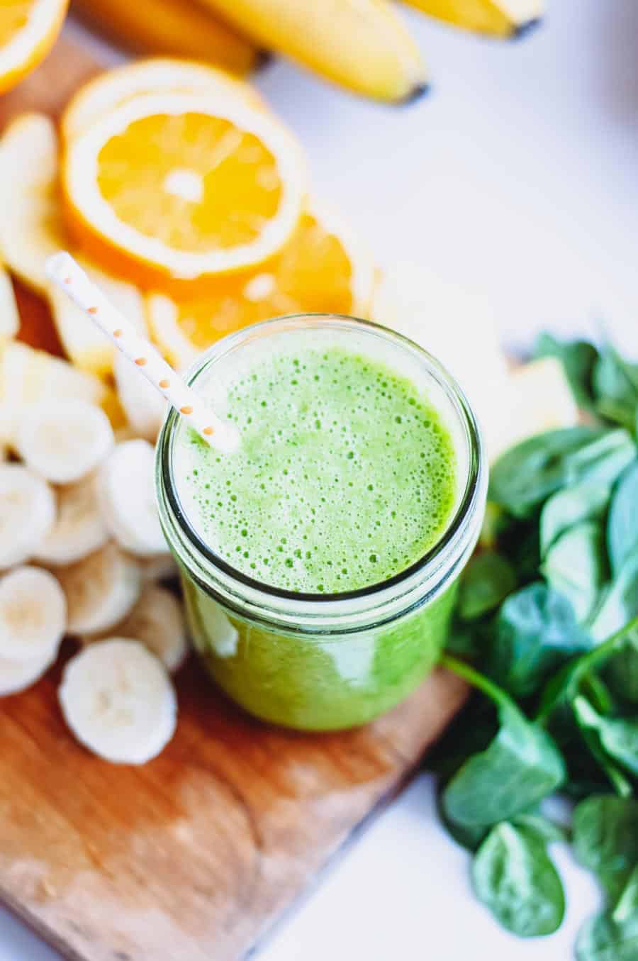 green smoothie in a glass jar with paper straw.