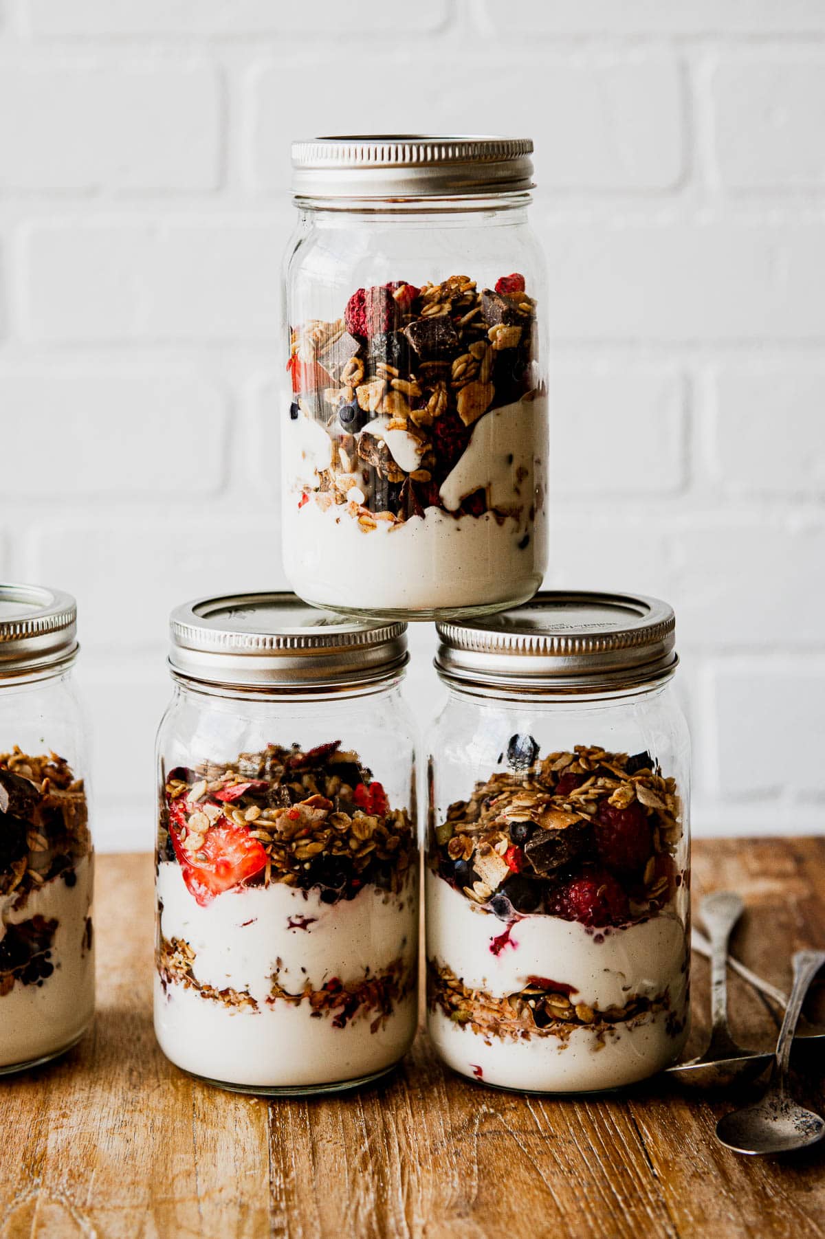 glass jars stacked on top of each other full of layered yogurt, granola and berries.