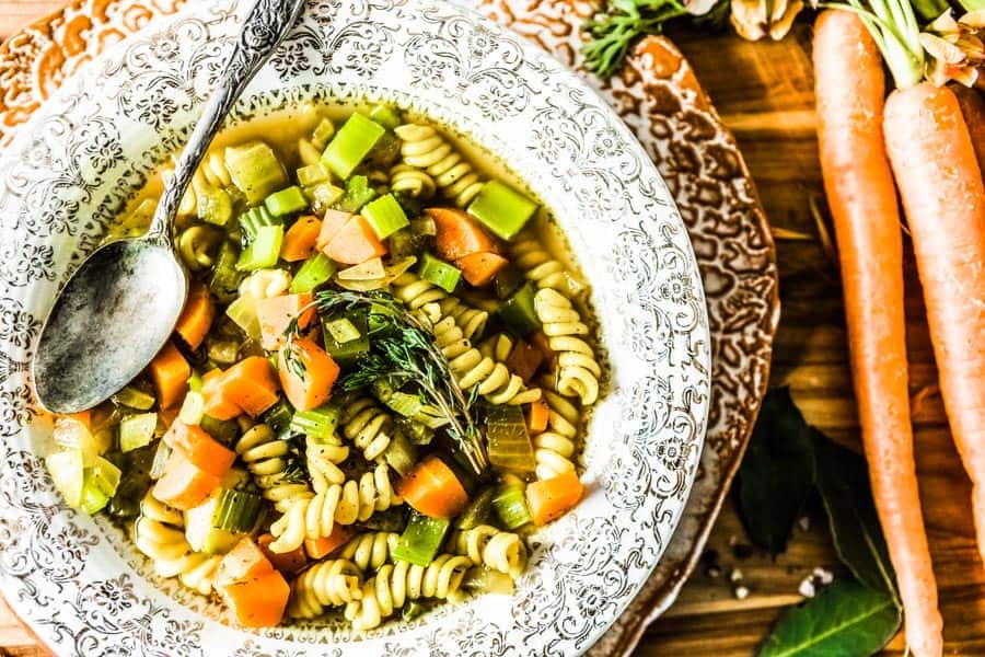 vegetable noodle soup in a decorative bowl with an antique spoon.