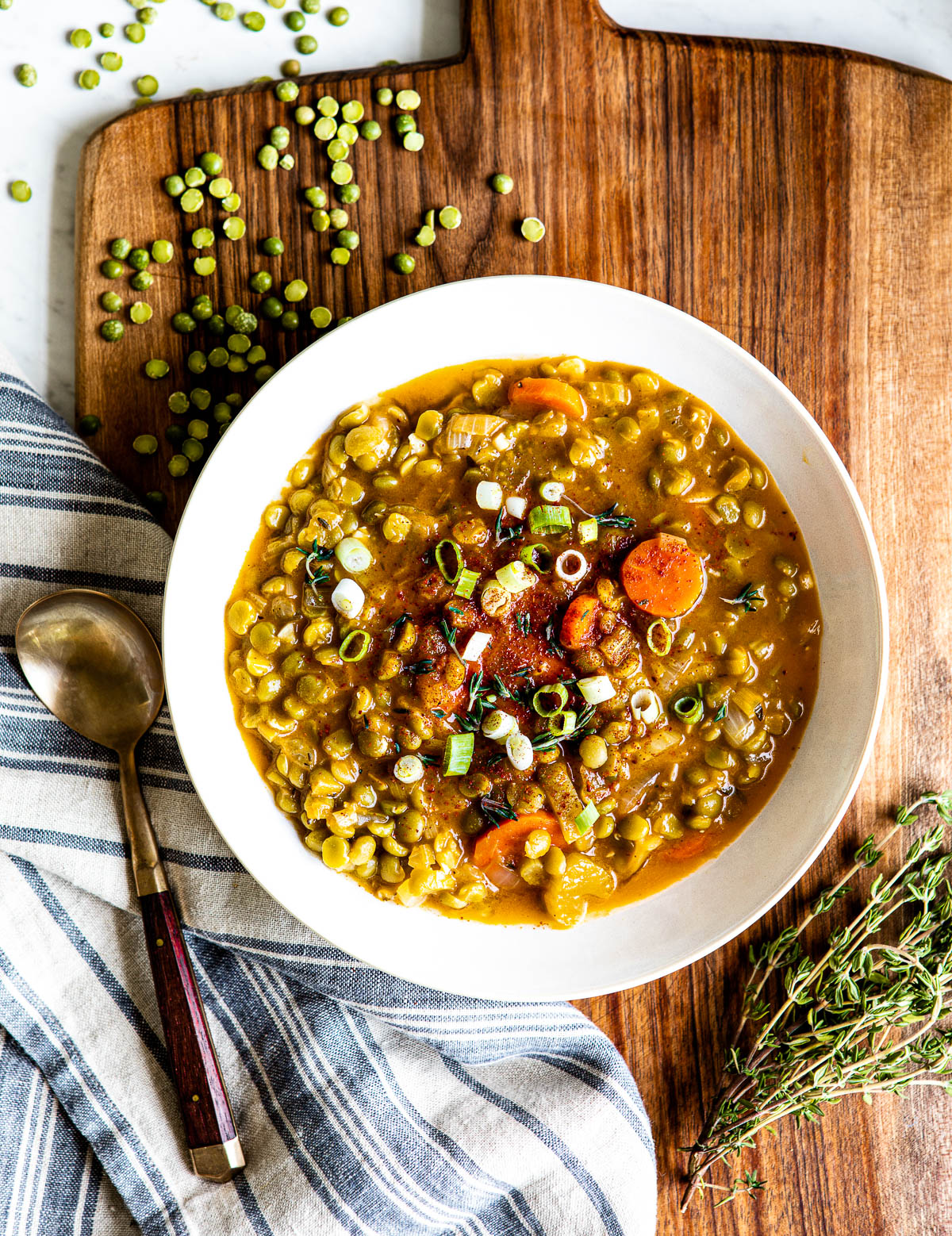 white bowl of vegetarian split pea soup on wooden slab.