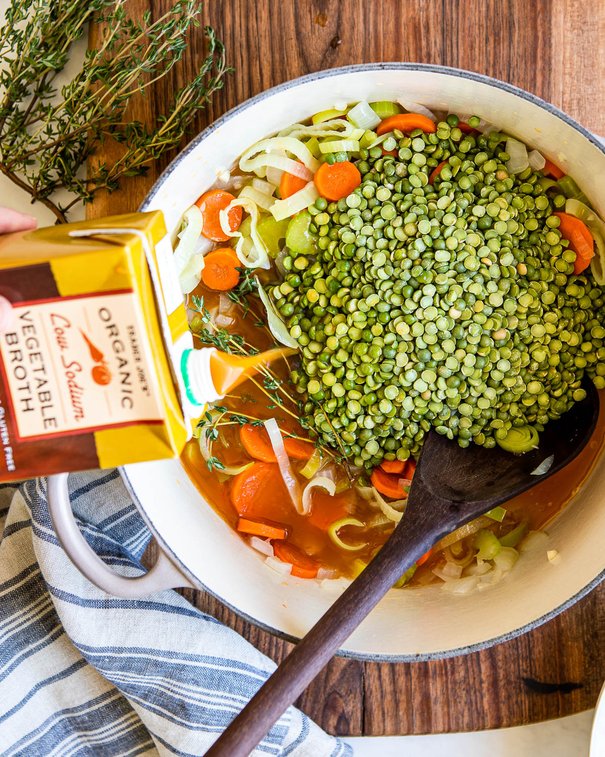 Pouring vegetable broth into pot of vegetarian split pea soup.