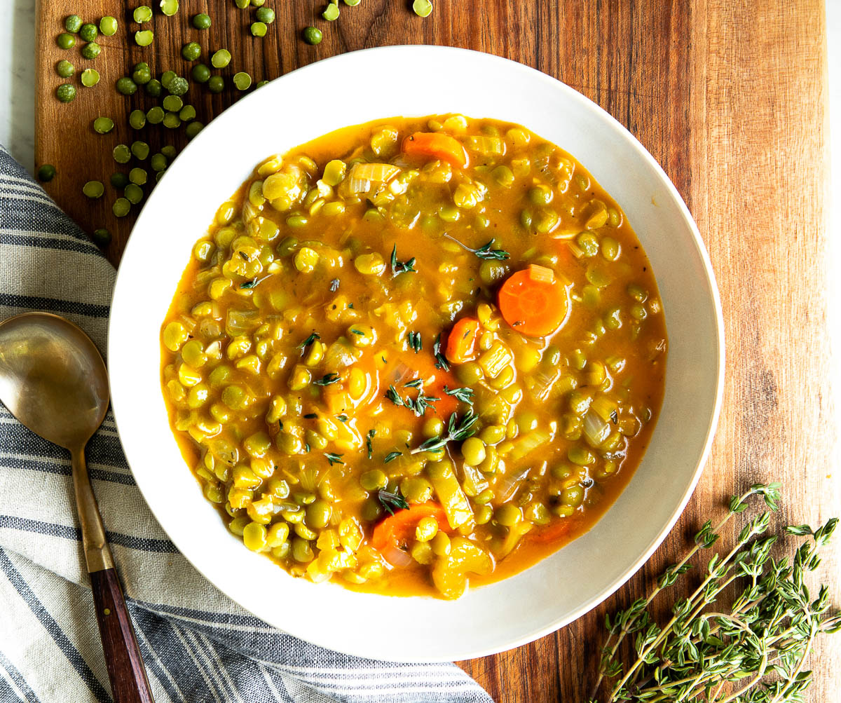 white bowl of plant-based soup next to a spoon.