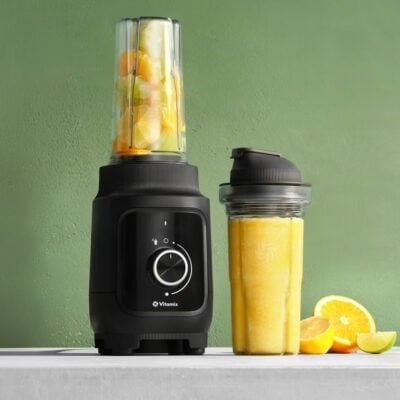 Vitamix blender making a fruit smoothie with fresh fruit on the side.