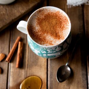 A cozy cup of warm almond milk topped with a sprinkle of cinnamon, served in a rustic white mug.