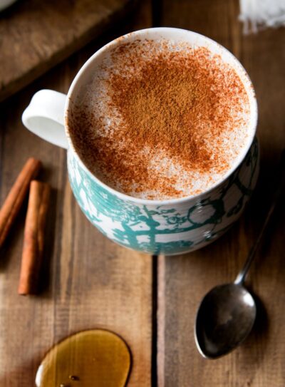 A cozy cup of warm almond milk topped with a sprinkle of cinnamon, served in a rustic white mug.