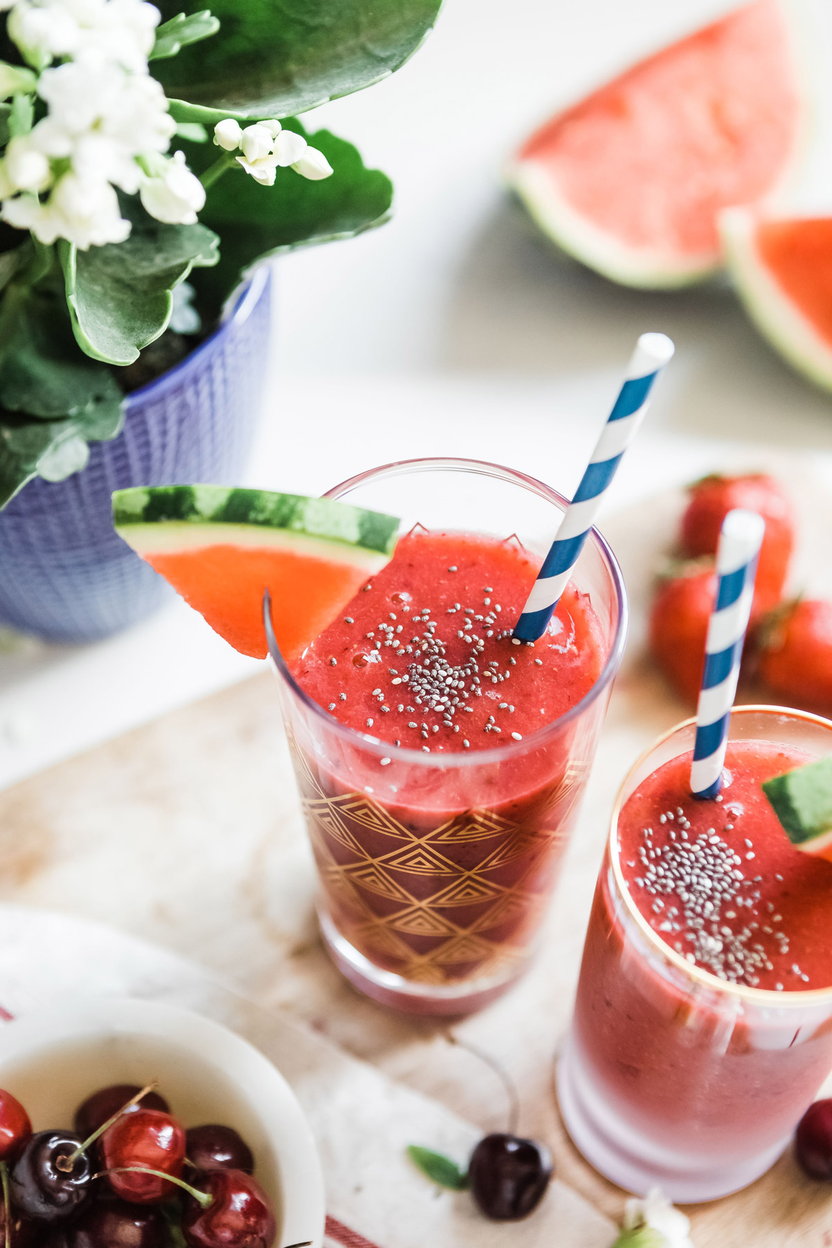 Watermelon smoothie garnished with chia seeds, served in a glass with a paper straw.