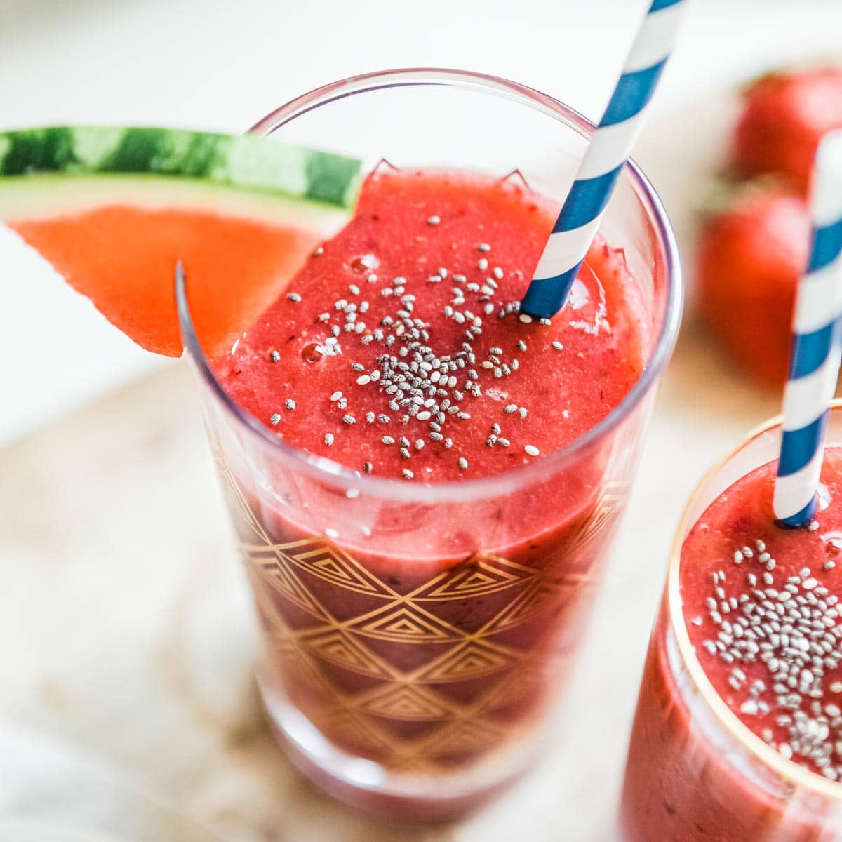 watermelon smoothie in a gold flecked glass with a paper straw.