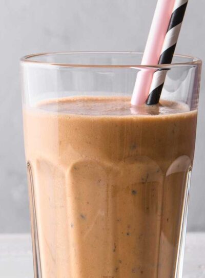 Glass of a delicious chocolate weight loss shake with a pink straw and a black and white striped straw