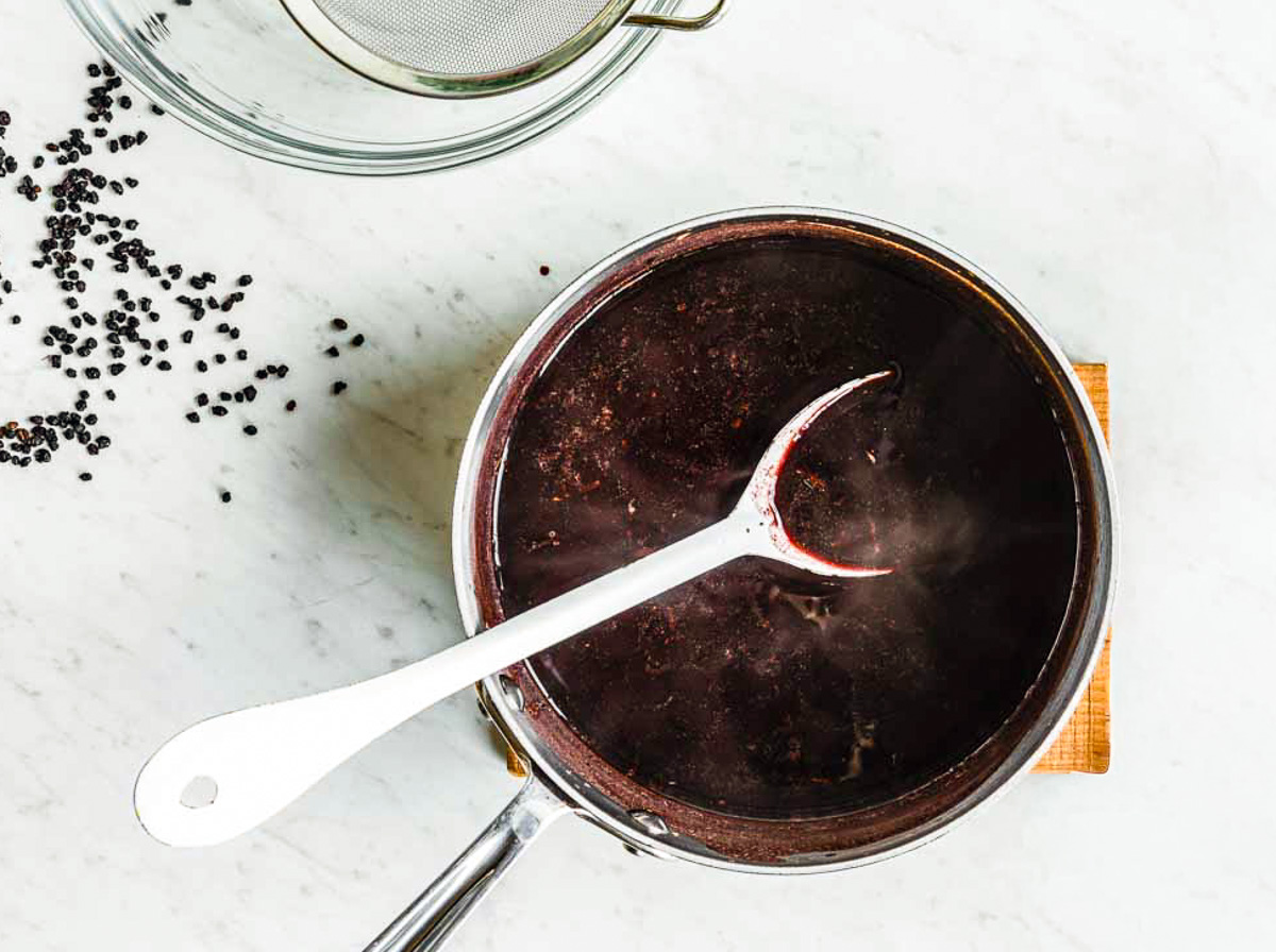 Homemade elderberry syrup simmering in a pot