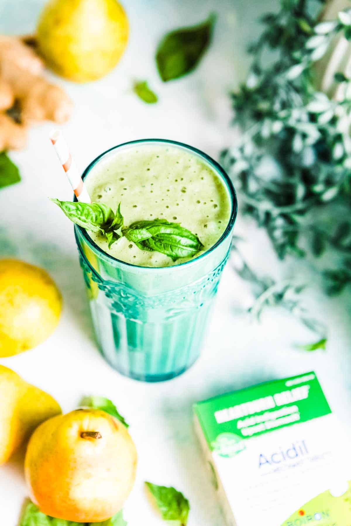 A glass full of acid reflux smoothie, surrounded by fresh ingredients and a pack of Acidil.