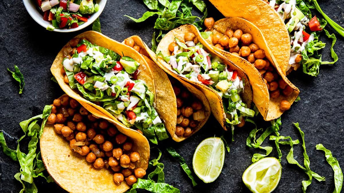 Spread of whole food plant-based recipes including tacos, soup, bowls and sides on a table