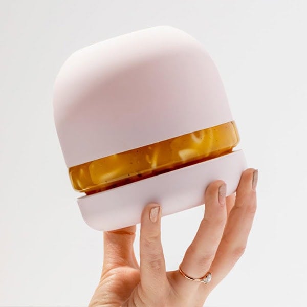 Hand holding a portable essential oil diffuser with a white and amber design.